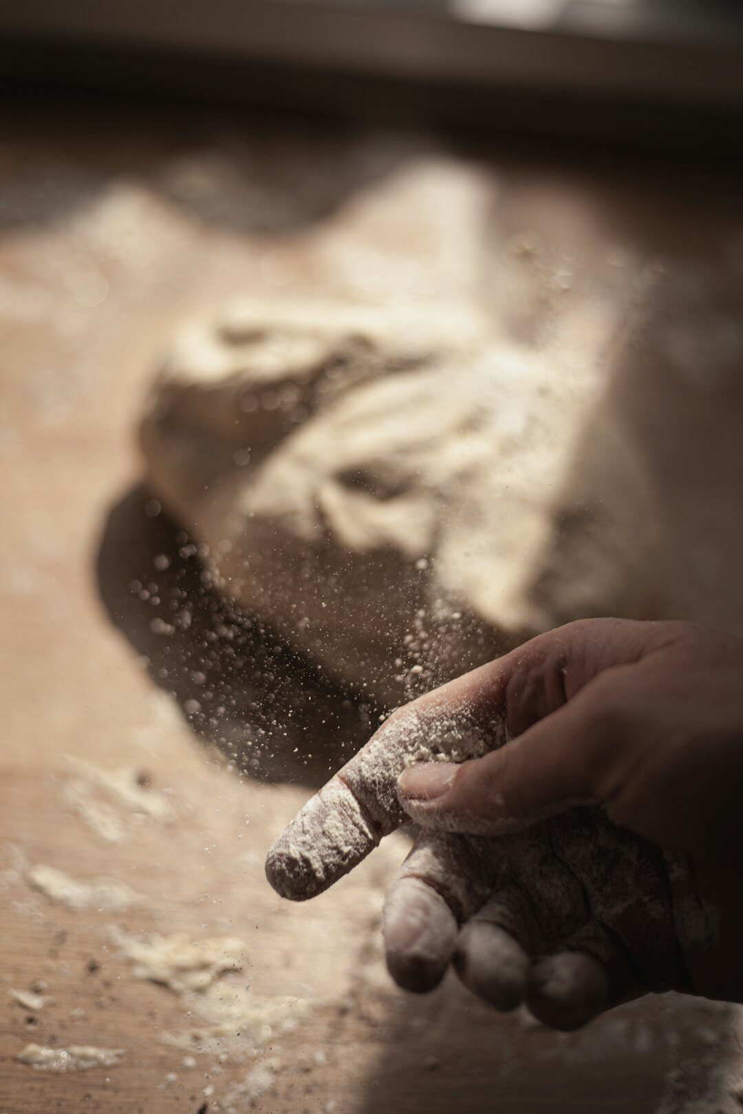 Hands kneading dough on a flour dusted wooden table